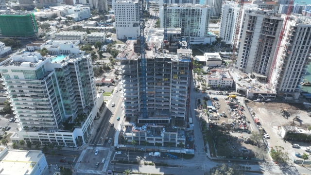 Aerial view of high-rise under construction with cranes near Sarasota Bay.