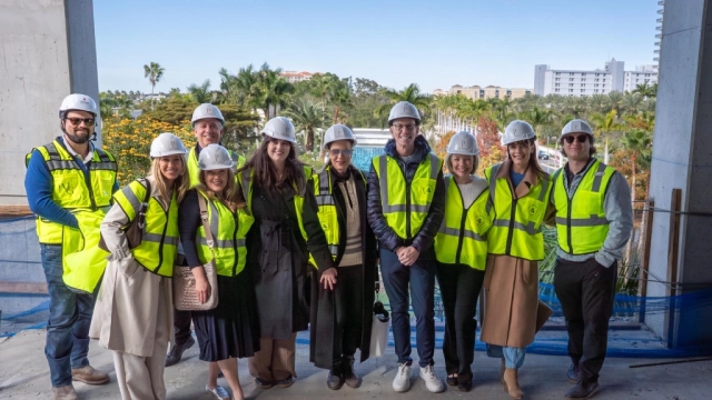 Group wearing hard hats and safety vests at construction site.